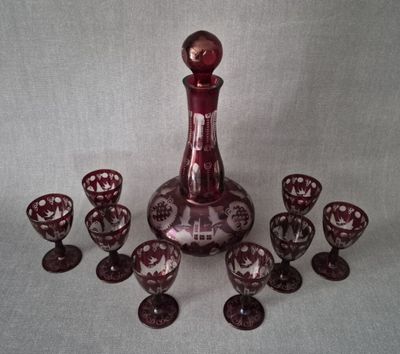 une carafe à vin et six verres à vin posés sur une table