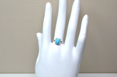 une main portant une bague, posée sur un mannequin