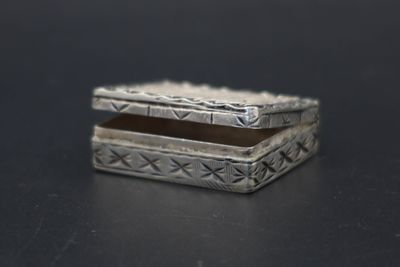 une petite boîte en argent posée sur une surface noire