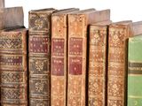 many old books lined up on a shelf in a row
