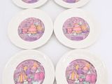 six white plates with purple designs on them sitting on a white surface