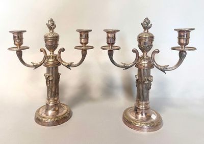 deux bougeoirs en argent posés l'un à côté de l'autre sur une table