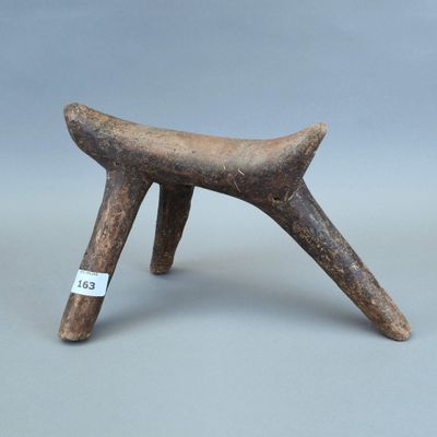 un vieux tabouret en bois posé sur une surface grise