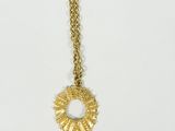 a gold necklace with a sunburst pendant on it