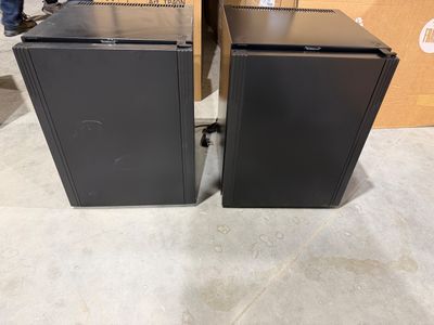 Deux enceintes noires sont posées l'une à côté de l'autre sur une table