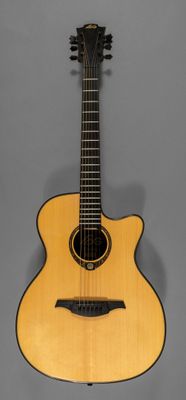 un gros plan d'une guitare acoustique sur fond gris
