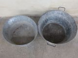 two metal buckets sitting on the ground next to each other