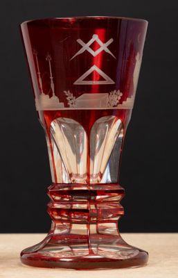 un verre rouge posé sur une table en bois, sur fond noir