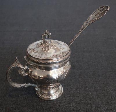 une théière ancienne en argent avec une cuillère, sur fond noir