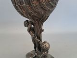 un vase en argent orné d'un oiseau, posé sur une table