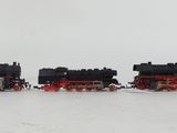 three black and red trains sitting on a white surface