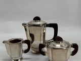 three pieces of silver tea and coffee set on a white surface