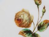 a white plate with a yellow rose painted on it