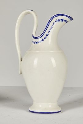 un pichet blanc et bleu posé sur une table à côté d'une tasse