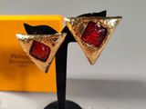 pair of red and gold triangle shaped earrings on a black stand