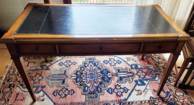 un bureau au plateau noir posé sur un tapis dans une pièce
