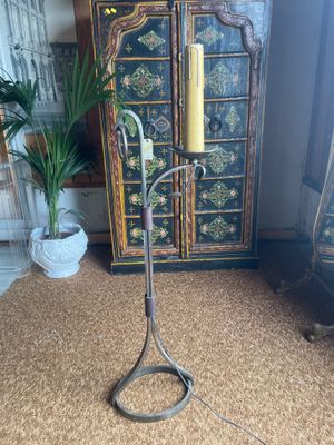 an old fashioned floor lamp with a candle on top of it