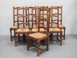 six wooden chairs are lined up in a row on a gray floor