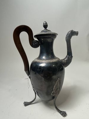 a silver tea pot with a wooden handle on a stand