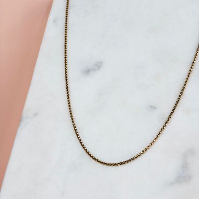 un collier à chaîne en or posé sur une surface en marbre