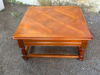 a small wooden table with a wooden top on the ground