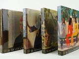 three books are lined up on a white surface, one is a painting and the other is a painting