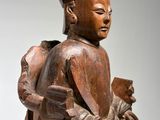 une image représentant une statue en bois d'un homme tenant un livre