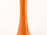 an orange vase on a white surface with a white background