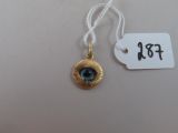 une photo d'un pendentif « œil maléfique » doré et bleu, avec une étiquette de prix