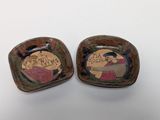 pair of ceramic ashtrays with hand painted scenes of a man and a woman