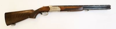 un fusil de chasse posé sur une surface blanche, muni d'une crosse en bois