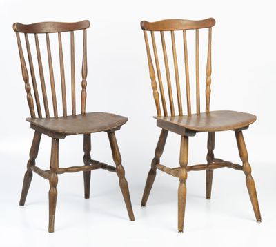 two wooden chairs sitting next to each other on a white surface