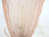 a pink glass vase with a yellow handle on a table