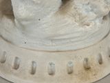 a figurine of a hand holding a bird on a pedestal