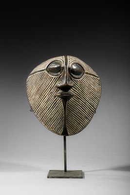 une image représentant un masque en bronze posé sur un socle