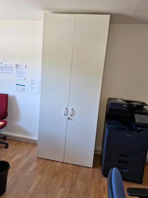 une pièce équipée d'un bureau, d'une chaise, d'une imprimante et d'une armoire