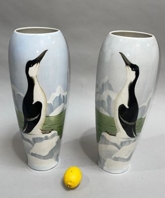two vases with birds painted on them sitting next to a lemon