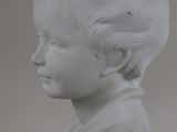 a white marble bust of a boy with curly hair