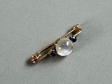 an image of a gold plated broochle with a white and blue bead