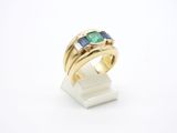 un gros plan d'une bague en or sertie d'une pierre verte et bleue