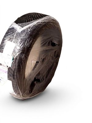 un rouleau de ruban adhésif emballé dans du plastique posé sur une surface blanche