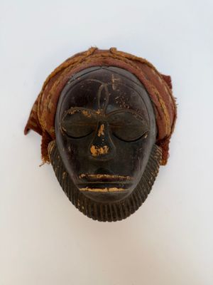 un vieux masque en bois accroché au mur d'une pièce blanche