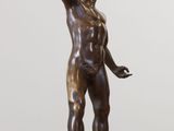 bronze statue of a man holding a book on a marble base