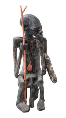 statue représentant un homme assis sur une chaise, un bâton à la main