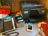 a desk with a printer, phone, and other office supplies
