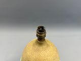 un vase jaune surmonté d'un couvercle marron, posé sur une table