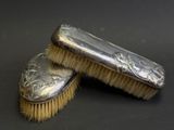 pair of antique silver plated brushes on a black background