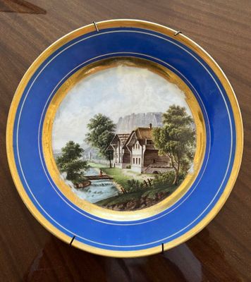 an image of a plate with a painting on it sitting on a table