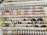 many rolls of wrapping paper on a shelf next to a pair of scissors