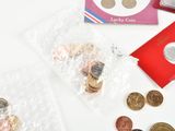 a bag of coins sitting on top of a table next to a red envelope